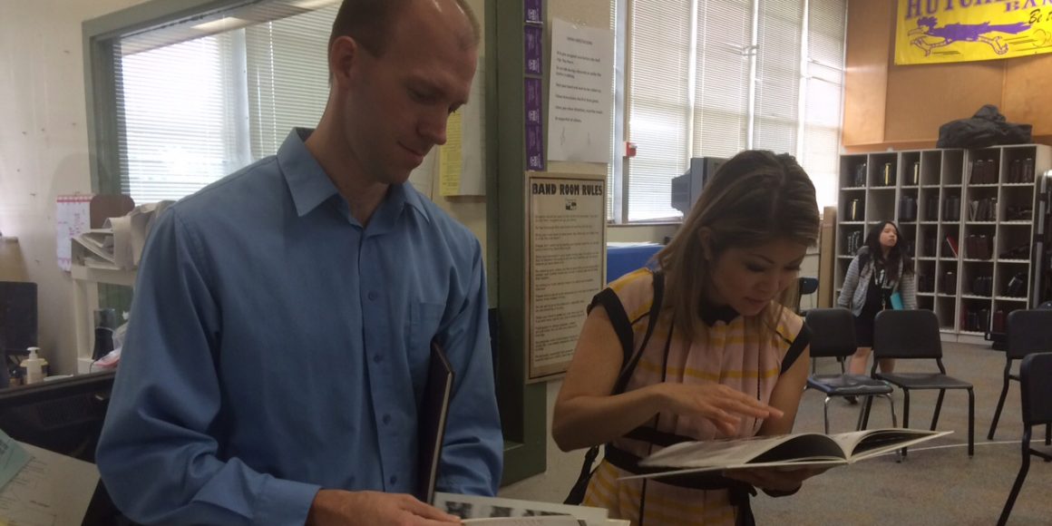 Mr. Lipcomb, Hutcheson's band director and CBS reporter Ms. Dinh look at old Hutcheson year books