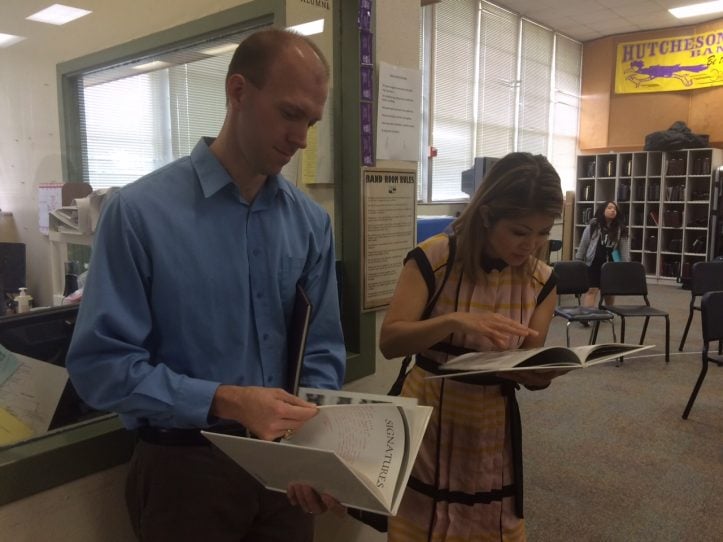 Mr. Lipcomb, Hutcheson's band director and CBS reporter Ms. Dinh look at old Hutcheson year books