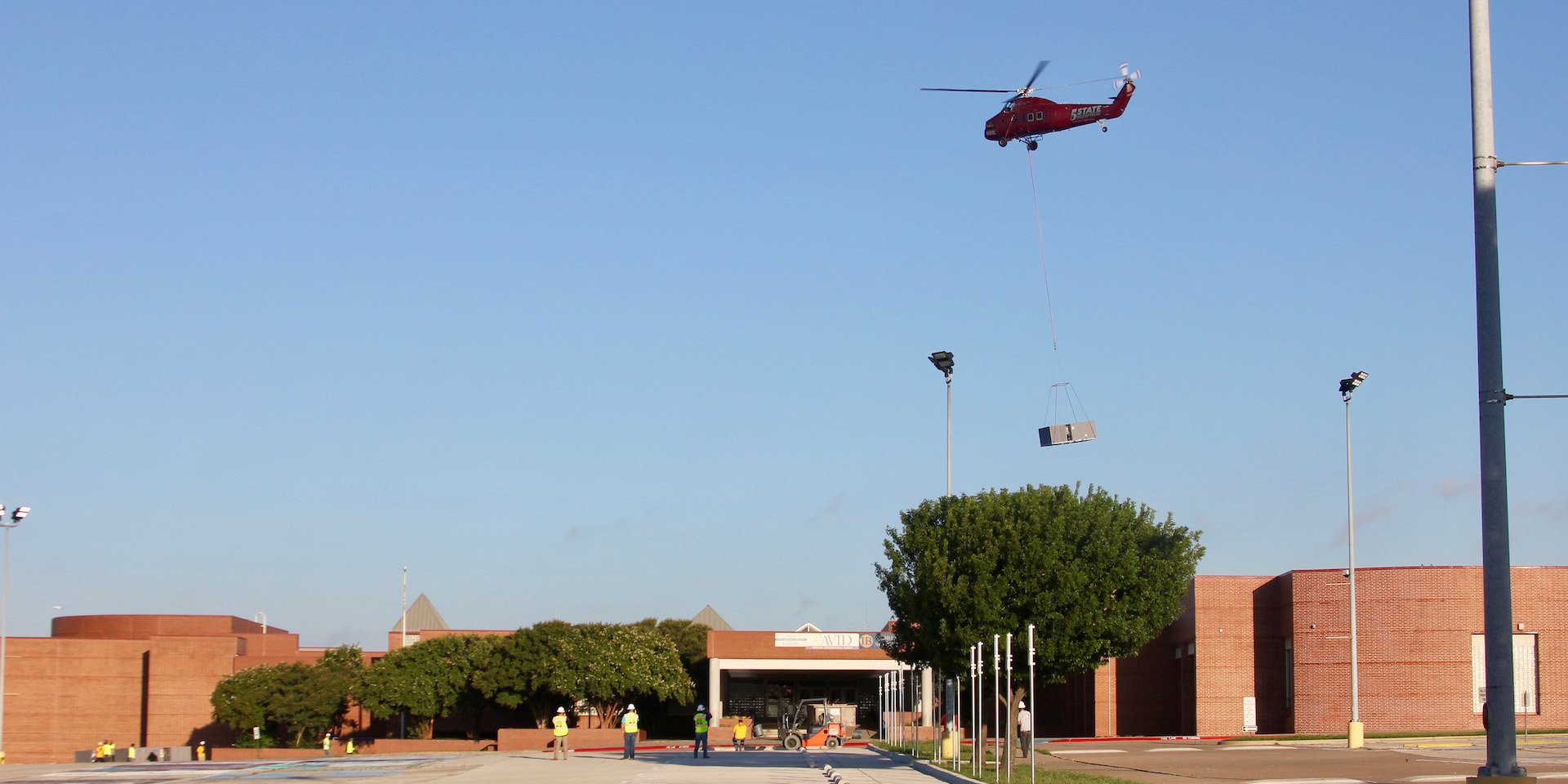 Helicopter lifts new HVAC RTUs to the Bowie High School roof