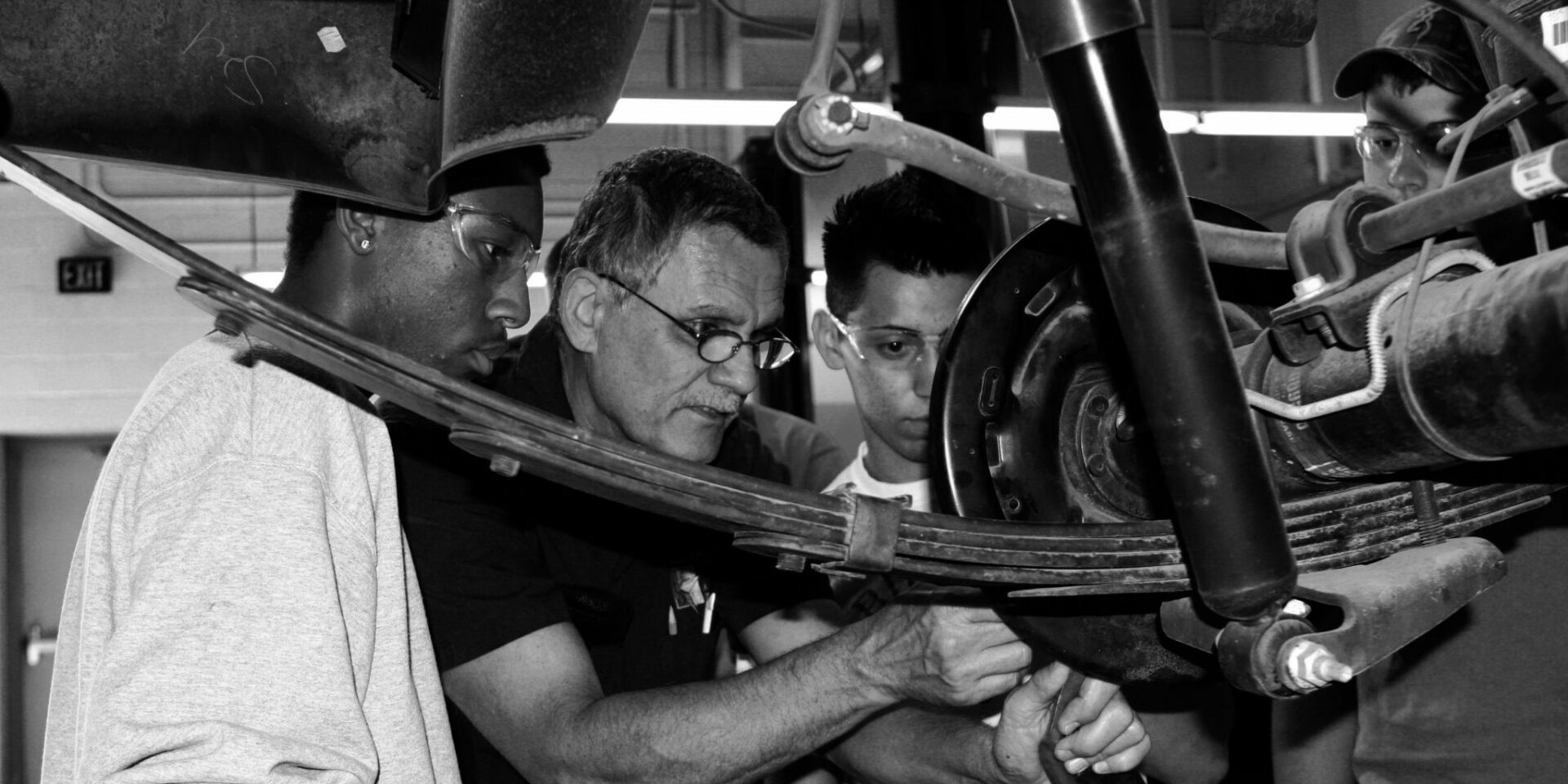 Automotive instructor showing students the components of motorcycle brakes
