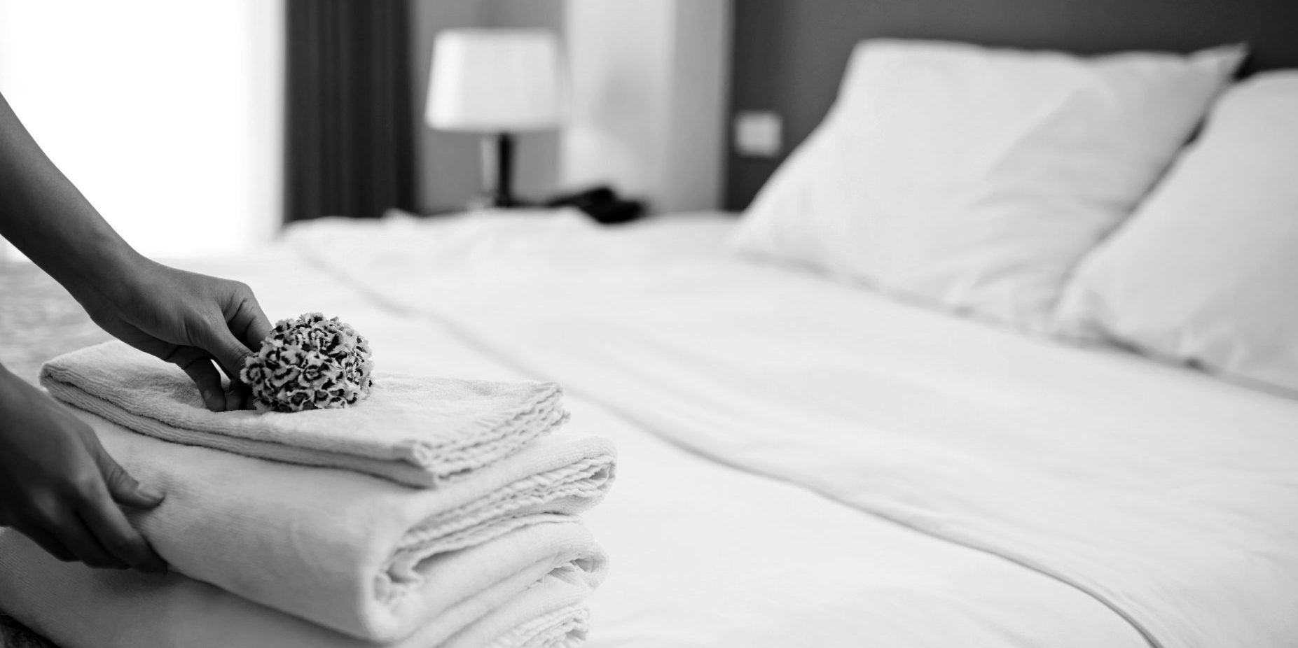 Hands of hotel maid putting flowers on the stack of towels