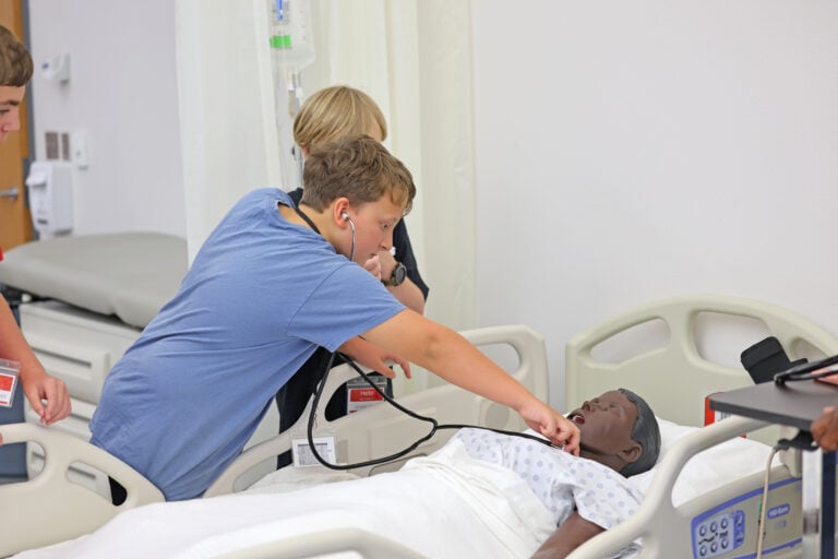 Student checks pulse on medical mannequin