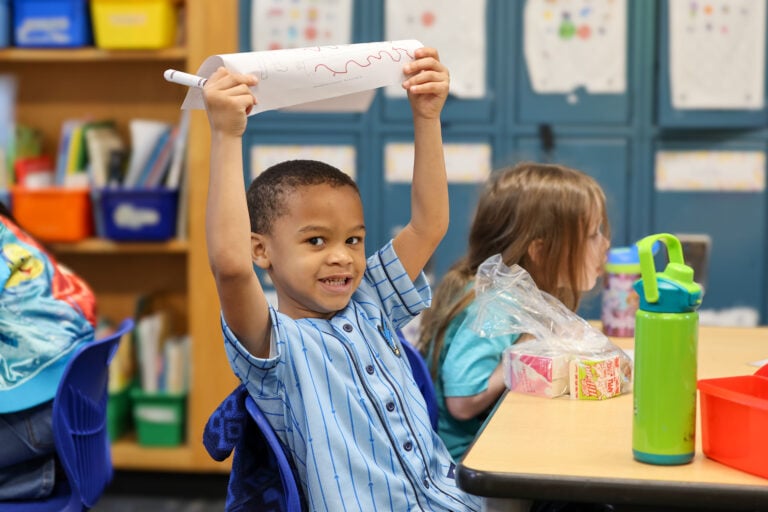 Pre-k student proudly displaying his work