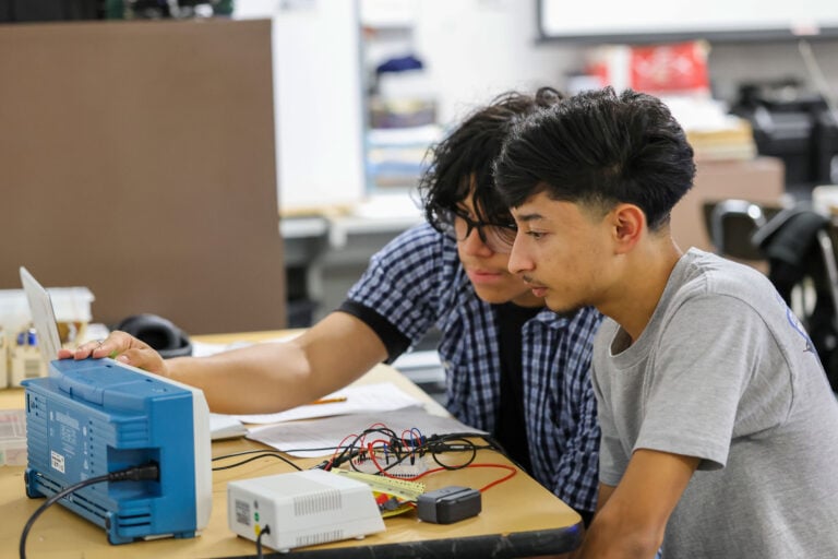 Two P-Tech at Sam Houston High School students examining a circuit